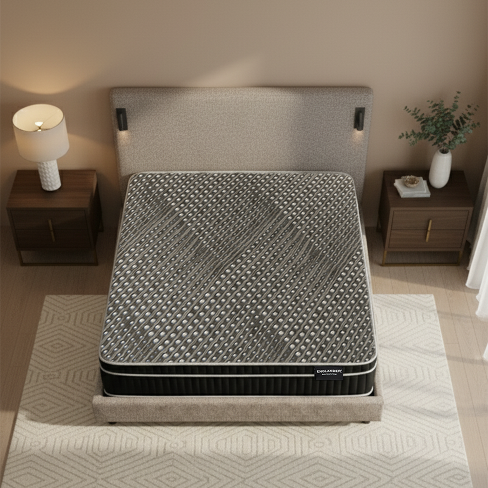 Gray mattress on a bed in a bedroom setting with nightstands and a lamp.