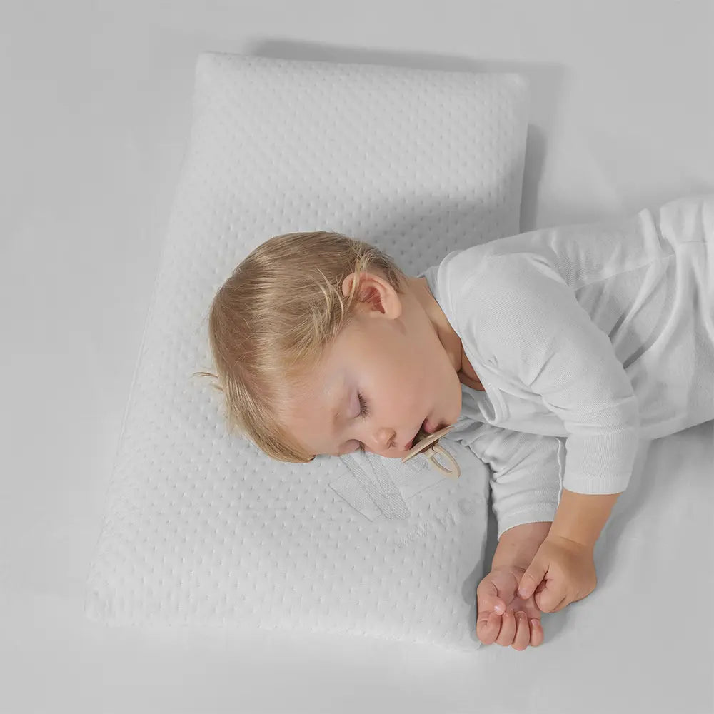 Child sleeping on a white pillow with a plain background