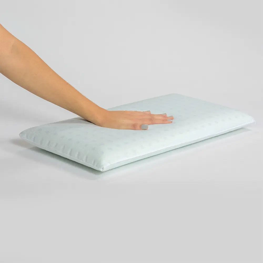 pillow on a white surface with a hand touching it